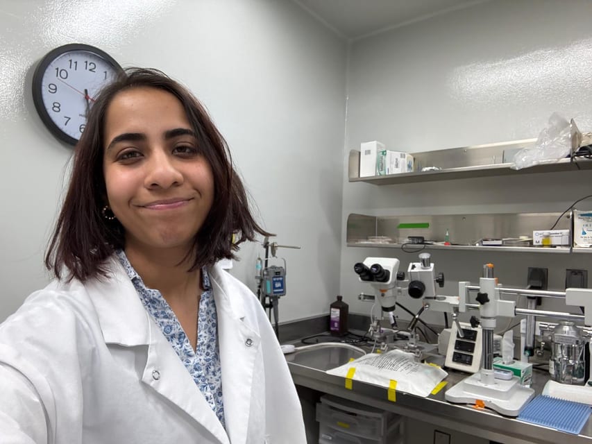 Shruti in the lab beside a surgical microscope rig