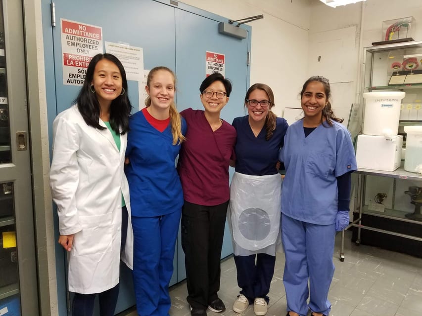 Shruti with colleagues in white coats and scrubs in a lab